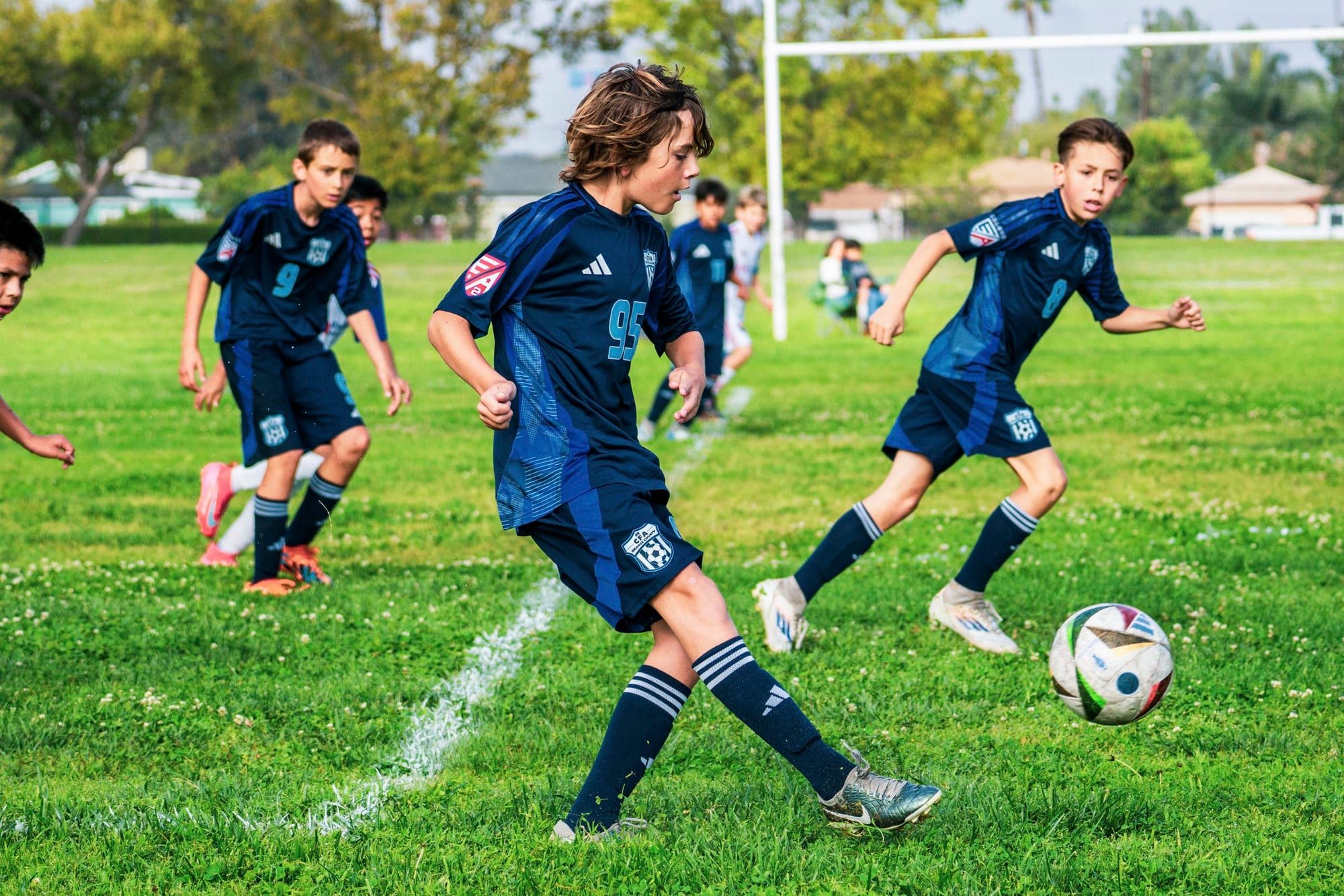 CFA boys in navy moving the ball through midfield