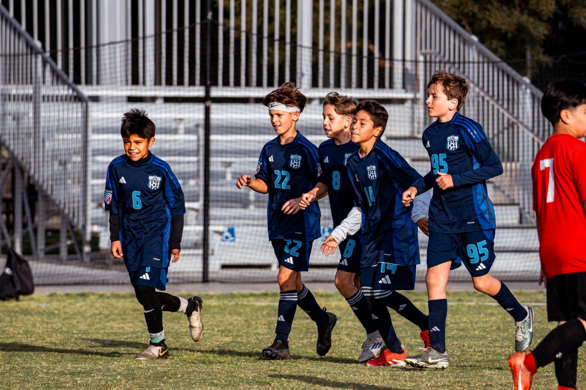 CFA boys in navy jogging back together after a goal