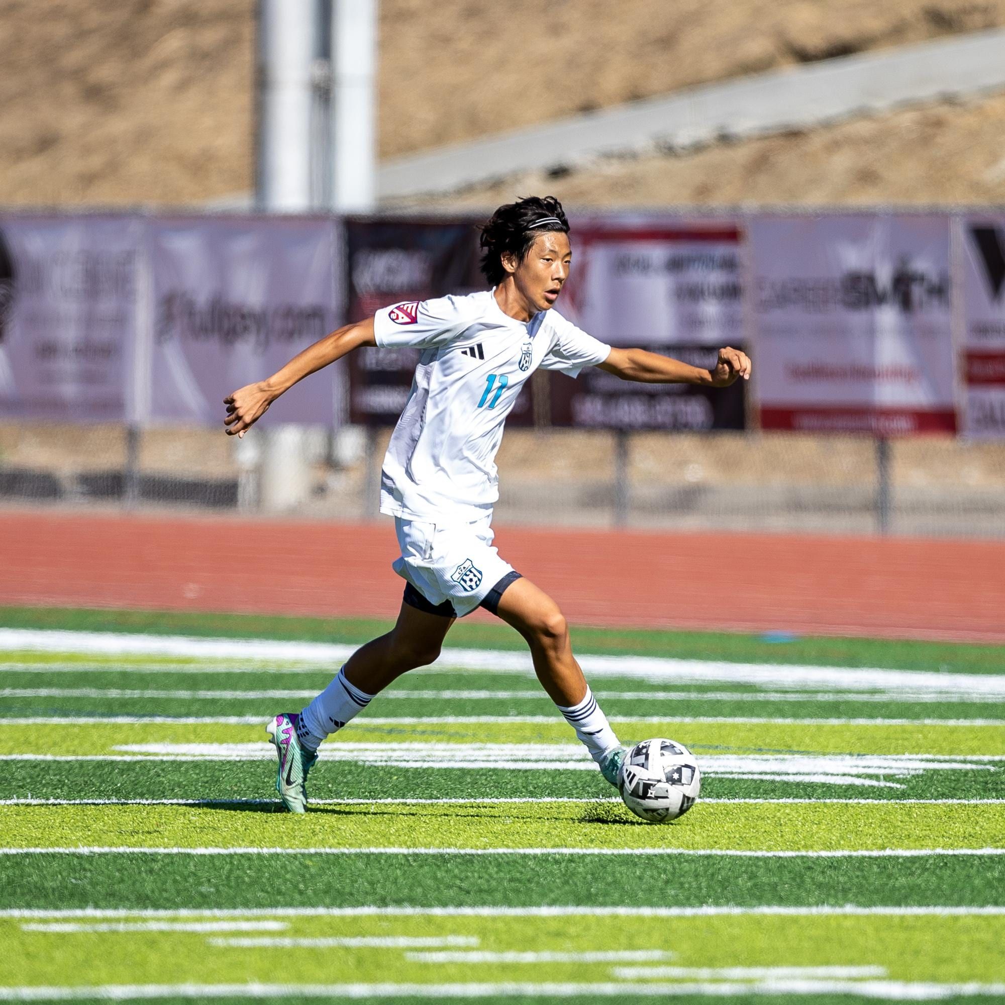 CFA boys player in white dribbling in a stadium