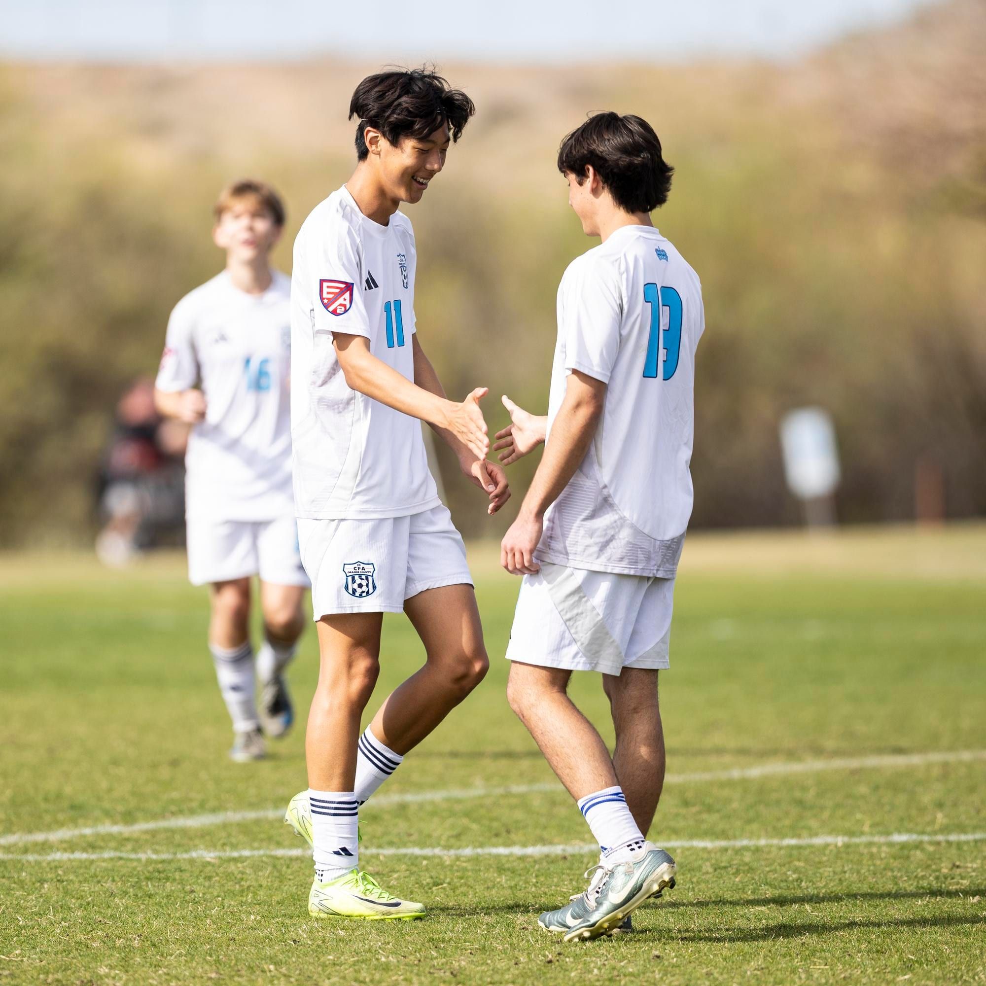 CFA boys players in white slapping hands on the field