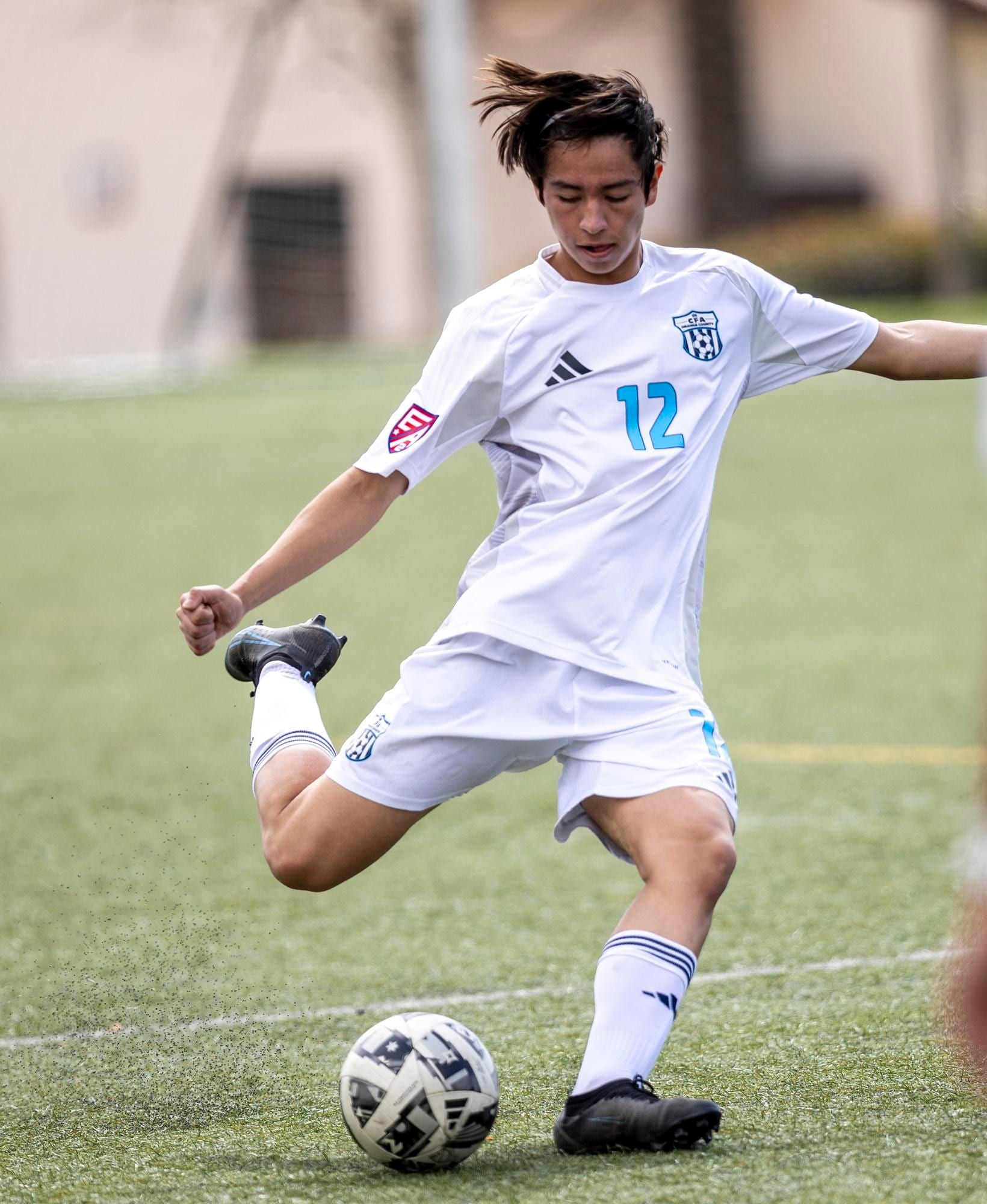CFA boys player in white winding up to strike the ball