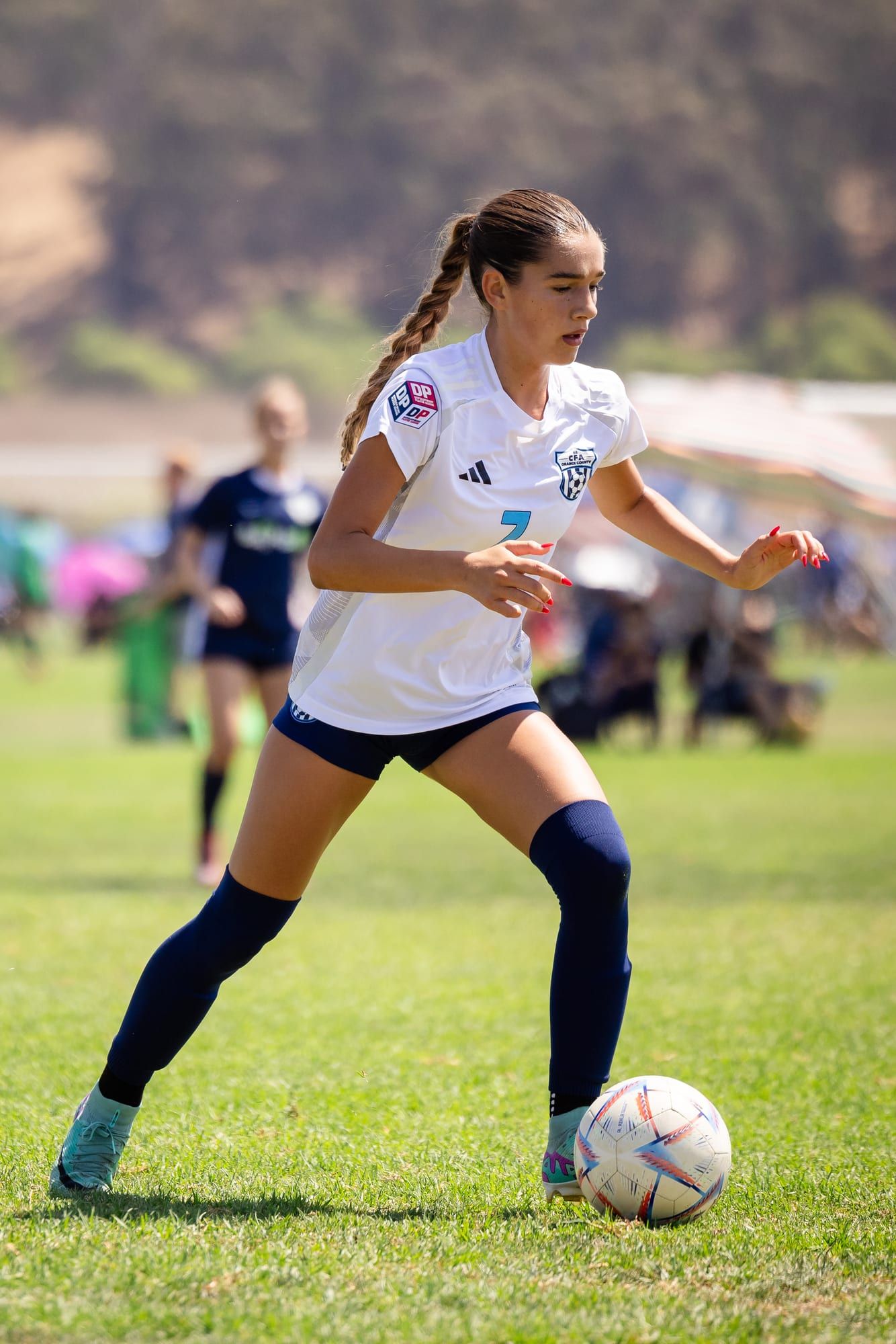 CFA girls player in white dribbling upfield