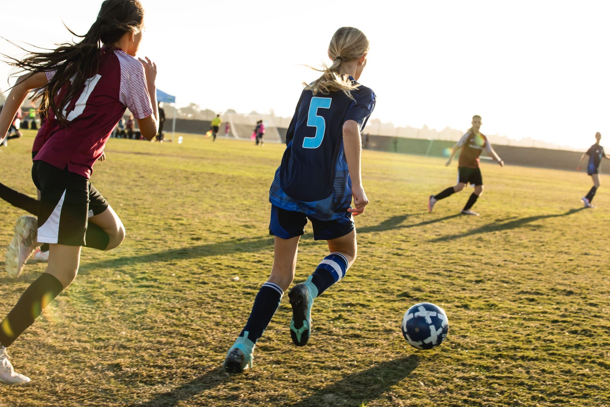 CFA girls player in navy dribbling in evening light