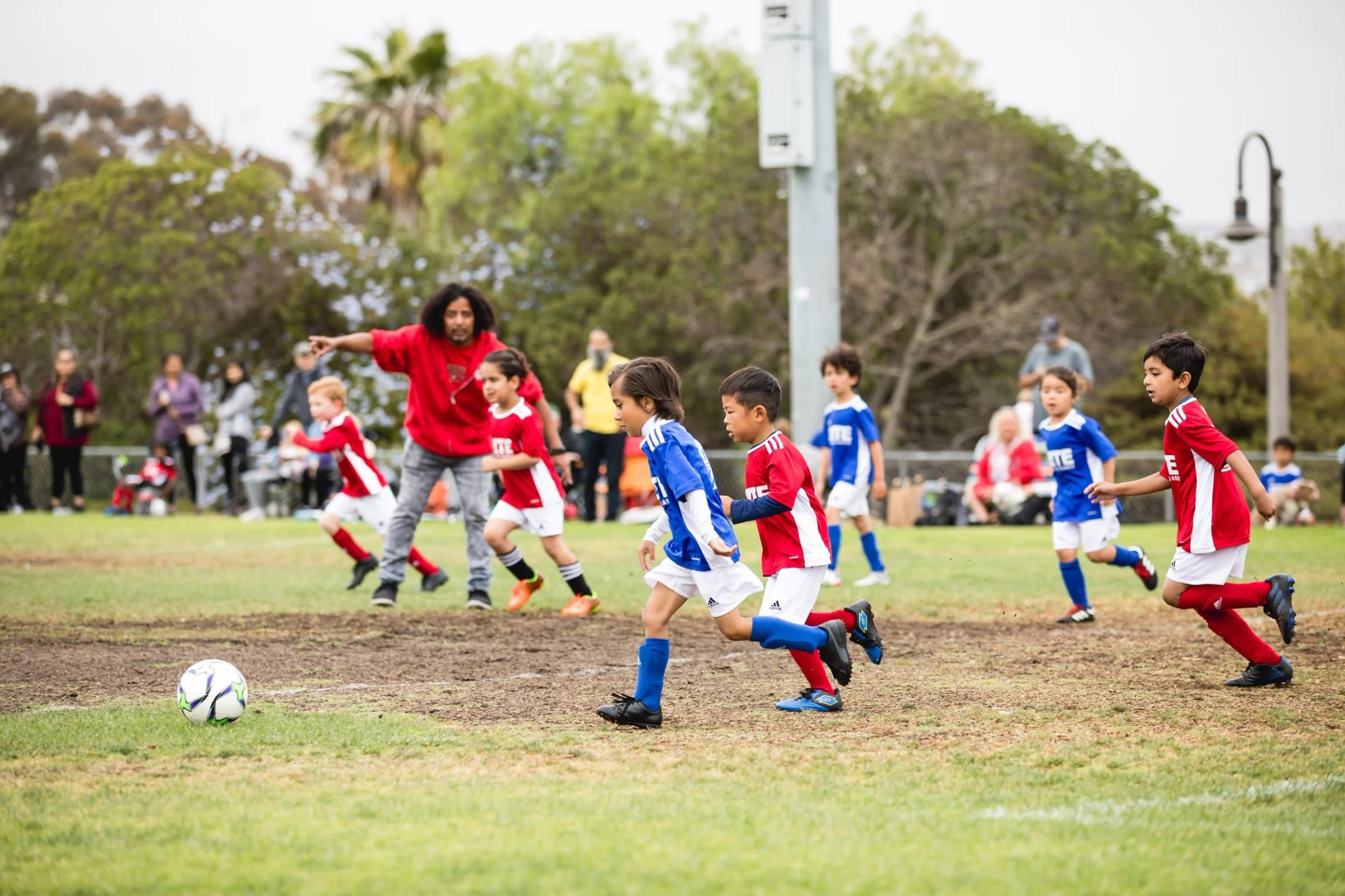 Young Elite Soccer League rec players in red and blue chasing the ball