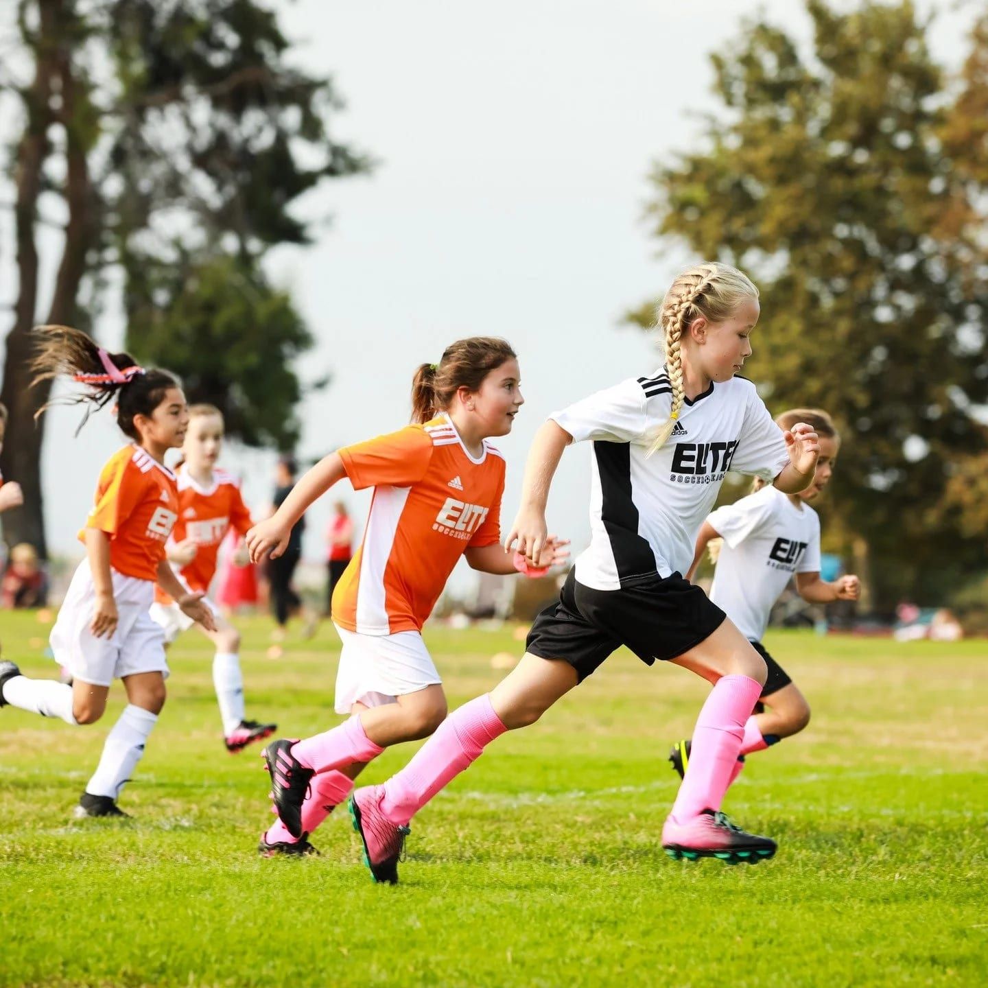 Young Elite Soccer League rec players in orange and white racing for the ball