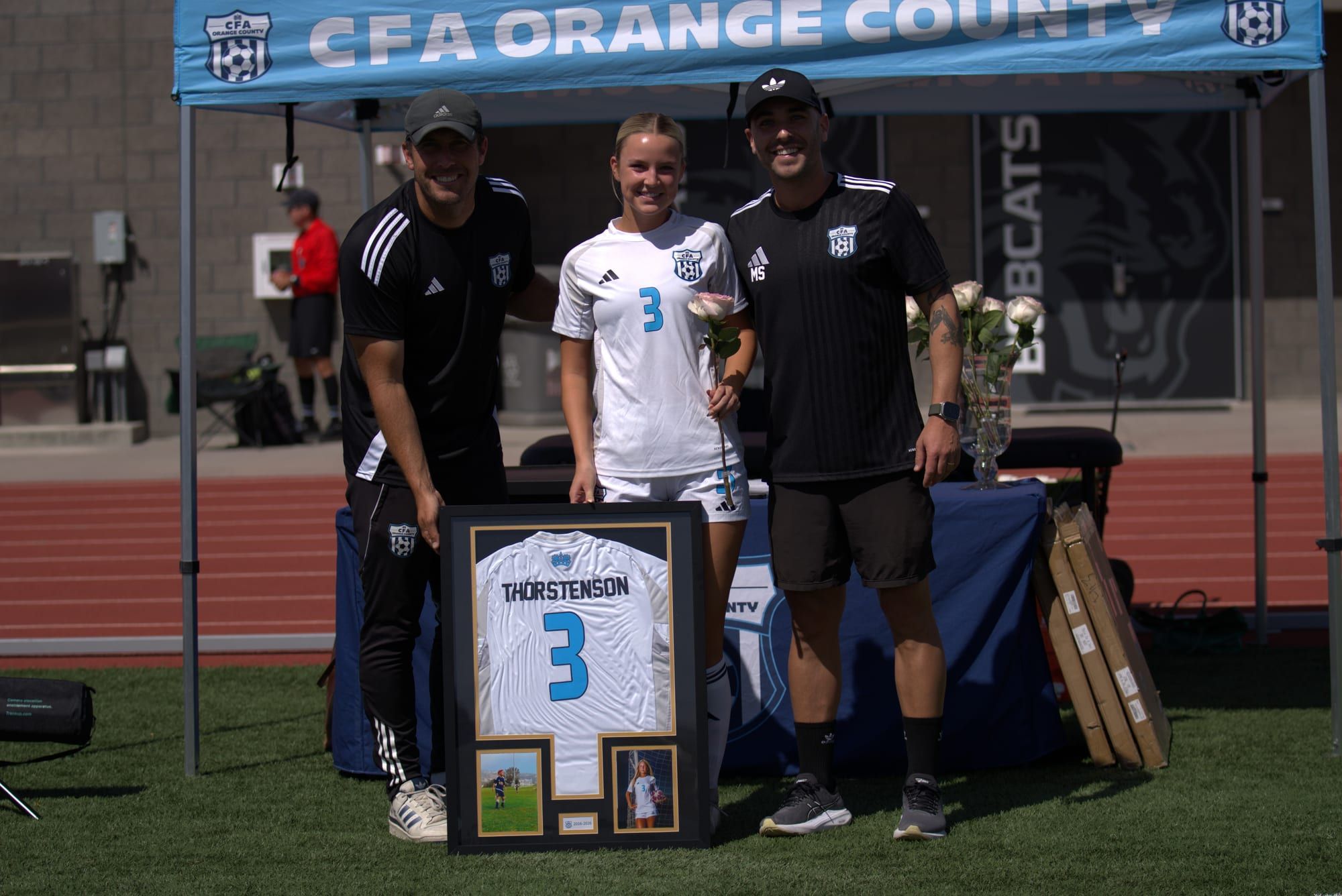 CFA senior receiving a framed jersey from coaches