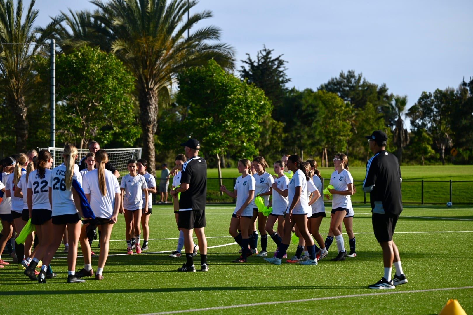 Players gathered for a team talk on a tree-lined field